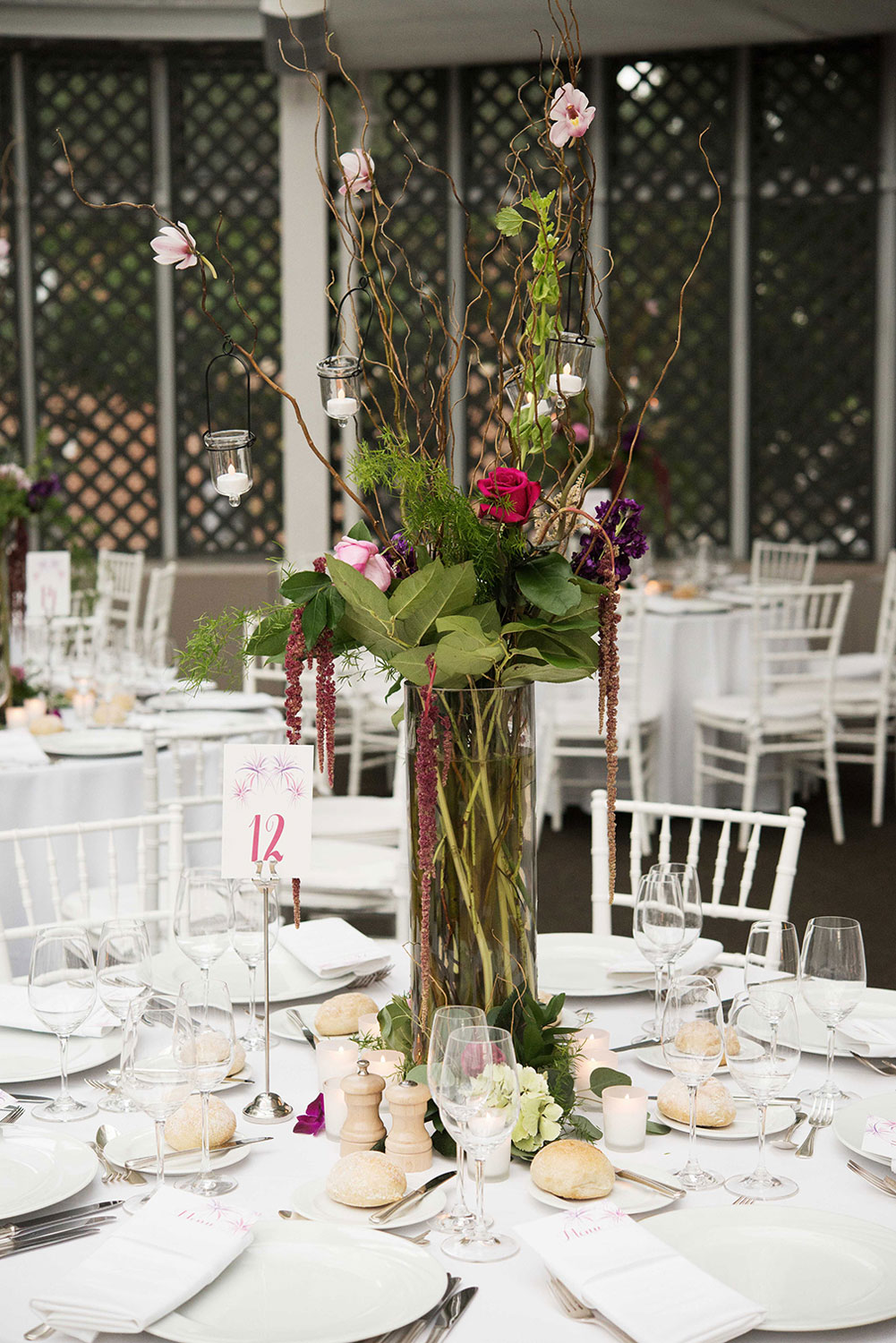 Tall wedding arrangements with Curly willow and hanging flowers with lanterns for a July wedding at the Brooklyn Botanic Garden